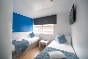 卢顿CiTi Hotel London Luton的配有两张床铺的小房间,拥有蓝色的墙壁