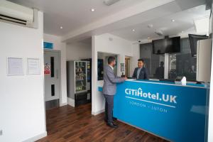 卢顿CiTi Hotel London Luton的两个男人站在商店里一个蓝色柜台后面