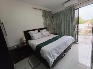 哈博罗内Manasseh Guesthouse的一间卧室设有一张床和一个大窗户