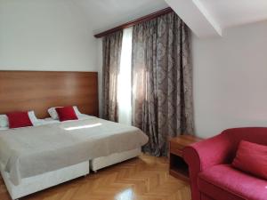 波德戈里察安拜塞多酒店的一间卧室配有一张床和一张红色的沙发