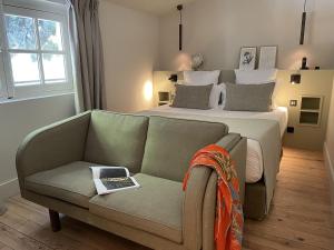 莱博德普罗旺斯布曼聂-普罗旺斯莱博酒店的一间卧室配有一张床和一张沙发,椅子上还有一本书