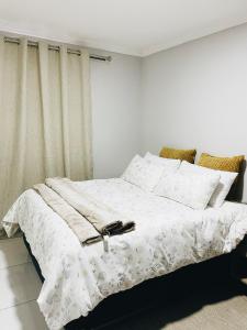马塞卢Stunning Modern Home in Maseru的一间卧室配有带白色床单和枕头的床。