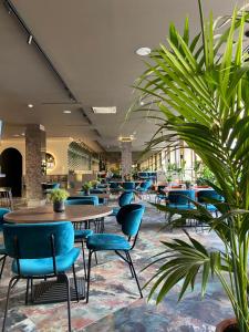 维尔纽斯CONTI HOTEL VILNIUS, Conference Centre, Restaurant & Bar的一间食堂,配有桌椅和植物