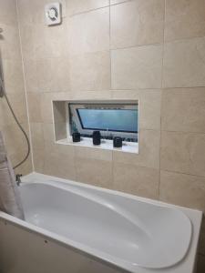 伦敦Manhattan Studio flat northbridge services的带浴缸的浴室以及墙上的电视。