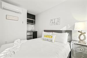 南迈阿密Sunset Inn-South Miami的白色卧室配有一张白色大床和黄色枕头