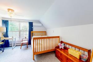 South ThomastonPleasant Beach Road Retreat的一间卧室配有一张婴儿床、一张桌子和一张书桌。