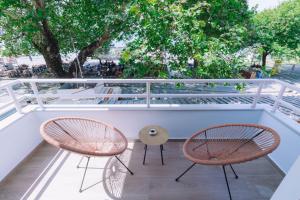 纳弗帕克托斯Vallia Suites-Green Luxury Suite A3的树木繁茂的阳台配有两把椅子和一张桌子