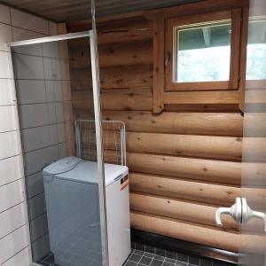 锡尔卡Levihaukka 10的浴室设有木墙,配有洗衣机和烘干机