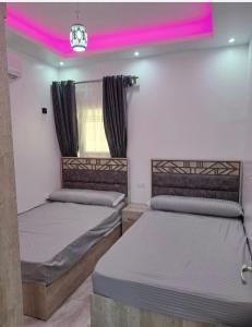 赫尔格达SELENA BAY RESORT HURGHADa的配有粉红色照明的客房内的两张床