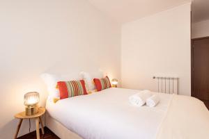 布拉加Braga 3BR Wonder by LovelyStay的卧室配有带毛巾的大型白色床