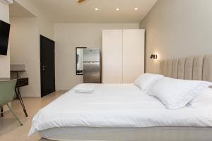 海法Carmel Studio By Carmel Boutique的卧室配有白色的床和冰箱。