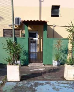 瓜鲁雅Parque Suites Com Ar Condicionado Piscina e Estacionamento的绿色建筑,有门和一些植物