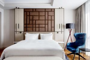 塞维利亚Radisson Collection Hotel, Magdalena Plaza Sevilla的一间卧室配有一张大床和一张蓝色椅子