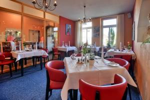 耶弗尔Hotel Im Schützenhof, Jever的一间设有白色桌子和红色椅子的餐厅