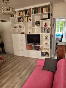 巴黎Appartement entier - Paris 12的客厅配有粉红色的沙发和书架