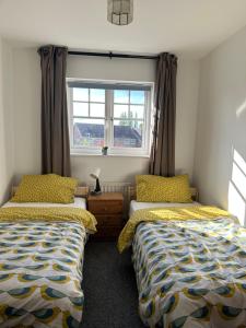 切辛顿Chessington Home Stay , 3 Bed 6 Guests Free Parking Near M25 JCT9, Chessington world of Adv Resort, Kingston, Epsom, Great for Families & Groups的一间卧室设有两张床和窗户。