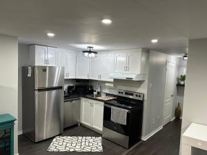 布兰普顿Luxurious and modern one bedroom basement suite.的厨房配有白色橱柜和不锈钢冰箱