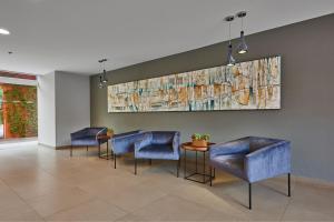 普埃布拉普埃布拉中央城市快捷酒店的一间设有蓝色椅子和墙上一幅画的等候室