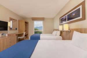 圣何塞City Express by Marriott San José Costa Rica的酒店客房设有两张床和一台平面电视。