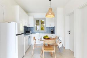 斯基亚索斯镇Skiathos Ammos Luxury Apartments的厨房配有白色橱柜和桌椅