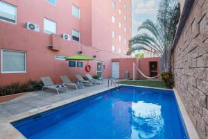 梅里达City Express Junior by Marriott Merida Altabrisa的粉红色建筑前的游泳池