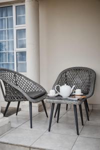 哈博罗内Mmaset Houses bed and breakfast的两张椅子和一张桌子,上面放着茶具
