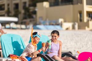 坎昆The Royal Sands Resort & Spa的两名年幼的儿童坐在沙滩椅上