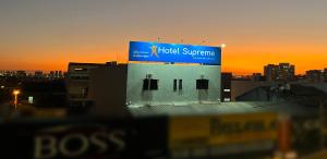 塔瓜汀加Hotel Supreme - Pistão Sul - Próximo ao Taguatinga Shopping的建筑顶部的标志,背景是日落