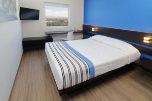 圣路易斯波托西City Express Junior by Marriott San Luis Potosi Zona Industrial的一间卧室配有一张床、一张书桌和一个窗户。