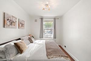 贝肯翰姆Cosy in Catford two bed near station的白色的卧室设有床和窗户