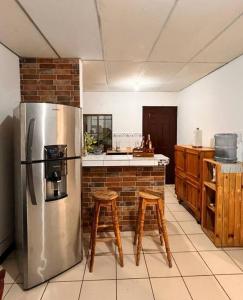 马那瓜Casa Tierra Viva的厨房配有不锈钢冰箱和木凳