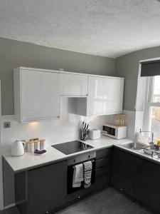 布莱顿霍夫Studio Apartment In Brighton & Hove的厨房配有白色橱柜和炉灶烤箱。