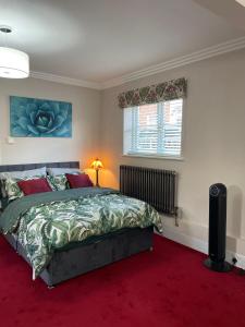 鲁特姆Luxurious and Elegant Homestay in Kent的一间卧室配有一张床,铺有红色地毯