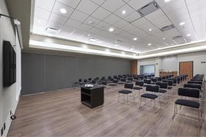 雷诺萨城市快线酒店的一个带椅子、讲台和屏幕的会议室