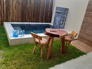 圣米格尔-杜斯米拉格里斯Marinho Suítes Milagres的一张木桌和两把椅子,旁边是游泳池
