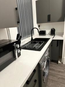 艾纯查姆Juz Apartments Manchester airport的厨房配有水槽和炉灶 顶部烤箱