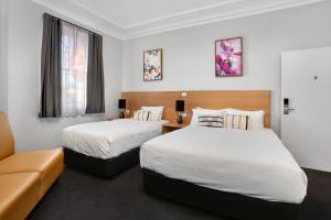 悉尼Penshurst Hotel的酒店客房,设有两张床和一张沙发