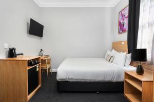 悉尼Penshurst Hotel的配有一张床和一张书桌的酒店客房