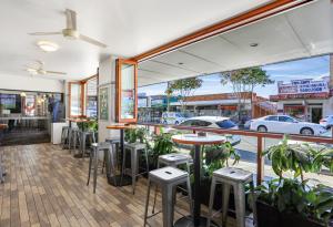 悉尼Penshurst Hotel的餐厅在窗户前设有桌子和凳子