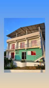 帕洛米诺Casa Guiwa Hostel的白色绿色的建筑,设有红色的窗户