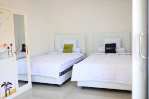 MarosUrbanview Hotel Eropa Maros Near Sultan Hasanuddin Airport的一间白色卧室,配有两张床和镜子