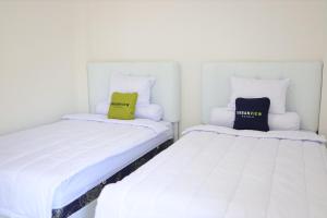 MarosUrbanview Hotel Eropa Maros Near Sultan Hasanuddin Airport的两张睡床彼此相邻,位于一个房间里
