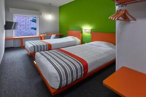 瓜达拉哈拉City Express Junior by Marriott Guadalajara Periferico Sur的绿色和橙色客房的两张床