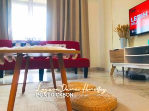 波德申Laguna Damai Homestay Teluk Kemang PD 3BR- Pool View的客厅配有桌子和红色沙发