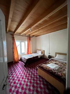 罕萨Karakorum Family Guest House Hunza的一间卧室配有两张床,铺有红地毯