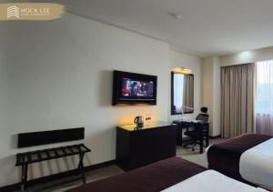 古晋Hock Lee Hotel & Residences的酒店客房配有一张床、一张书桌和一台电视。