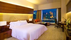 广州The Westin Guangzhou的酒店客房设有一张白色大床和一张书桌