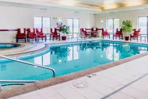 海伦娜Comfort Suites Helena Airport的酒店的大型游泳池设有红色椅子