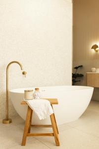 天鹅山White House Swan Hill的浴室配有白色浴缸和木凳