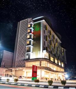 邦加槟港Grand Safran Hotel Pangkalpinang的一座大建筑,晚上有标志